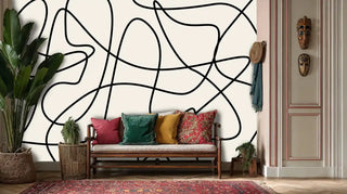 abstract curve wallpaper in beige and black, displayed in eclectic room with wooden bench and tribal masks