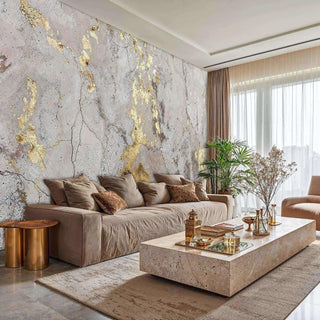 Abstract gold and concrete wall mural in a modern living room, featuring a large beige sofa and stone coffee table.