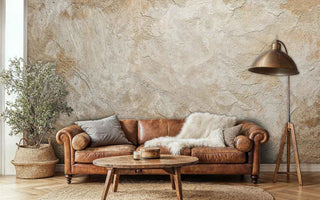 Aged plaster wallpaper featuring natural weathering patterns, shown behind vintage leather sofa