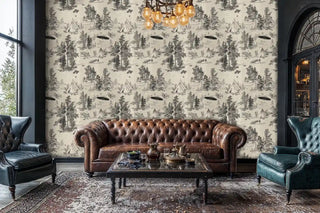 Alien forest wallpaper with UFOs, trees, and camping scenes in beige and black, shown in elegant living room with leather sofa