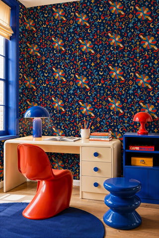 Angel and scrollwork wallpaper in deep blue and red, in a home office with red Panton chair