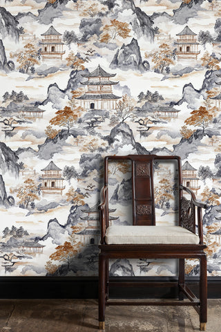 Asian ink wash wallpaper with pagodas and misty peaks behind a carved wooden armchair with cushion