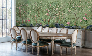 Asian-inspired wall mural with peonies and birds on green backdrop, in bright dining room with French chairs