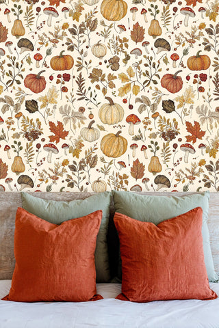 Autumn botanical wallpaper with illustrated pumpkins and berries, behind a rustic wooden headboard with terracotta pillows