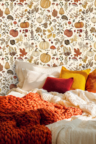 Autumn harvest wallpaper with pumpkins, mushrooms, and fall leaves on cream, in a cozy bedroom with chunky knit throw