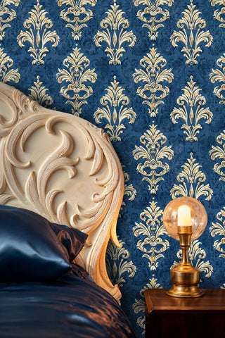 Baroque damask wallpaper in navy and gold with intricate scrollwork, featured in elegant bedroom with carved headboard