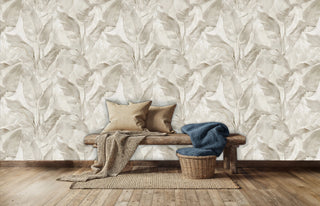Beige botanical wall mural with flowing leaf patterns, shown in cozy living room with wooden bench and woven basket
