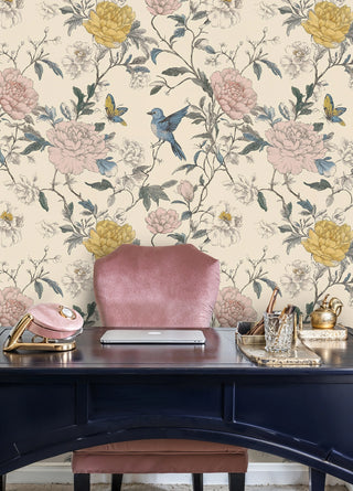 Bird and peony garden wallpaper in pink and gold tones, behind a navy desk with velvet chair