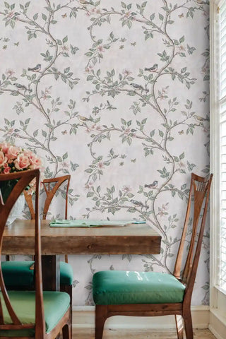 Birds and blossoms wallpaper featuring songbirds on flowering branches in soft pink and sage green, displayed in dining room with teal chairs