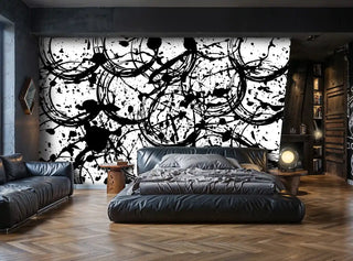 Black and white abstract wallpaper with paint splatters and circular motifs, featured in bedroom with leather furniture