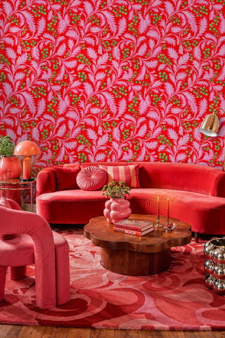Bold botanical wallpaper with pink acanthus leaves on red in a living room with curved red sofa
