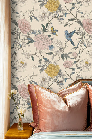Botanical bird and peony wallpaper with pink and yellow blooms, shown beside rose velvet pillows