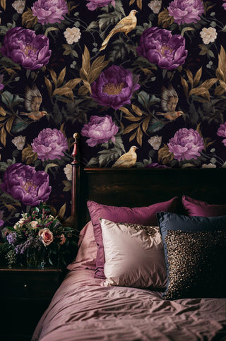 Botanical bird wallpaper with purple flowers on navy background shown in elegant bedroom with floral arrangement