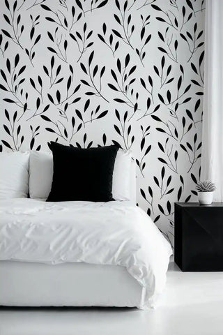 Botanical branch wallpaper with delicate leaves shown in minimalist bedroom with white bedding