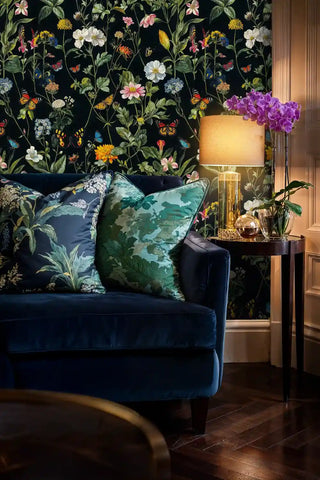 Botanical butterfly wallpaper featuring orange monarchs and pink blooms, shown in elegant living room with navy sofa