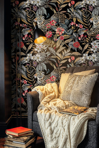 Botanical leopard wallpaper featuring spotted cats and flowers, displayed in cozy reading nook with armchair