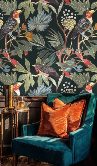 Botanical toucan wallpaper featuring dark birds and lush leaves, displayed in living room with teal velvet armchair