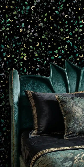 Celestial botanical wallpaper with golden moons and green leaves on black, shown in luxurious bedroom with teal velvet headboard