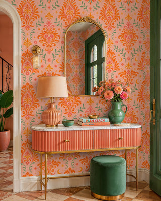 Celestial damask wallpaper with orange scrolls and pink blooms on blush, in an entryway with gold mirror and console