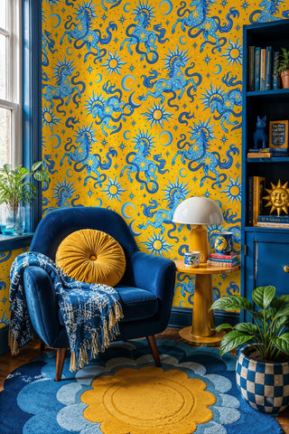 Celestial horse wallpaper with blue suns and moons on yellow, in a reading nook with navy velvet armchair