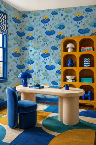 Celestial sky wallpaper featuring suns, moons, and shooting stars in a home office with yellow arched bookshelf