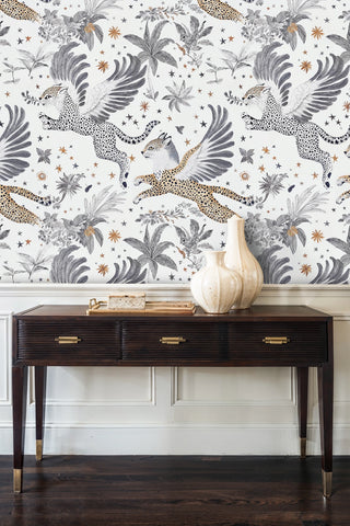 Celestial winged leopard wallpaper above wainscoting in an entryway with dark console and cream vases