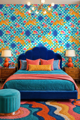 Checkered tiger wallpaper with colorful clouds and florals on teal, in a bold bedroom with velvet bed