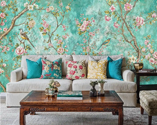 Chinoiserie botanical wallpaper with songbirds and blooms in living room with grey sofa and colorful throw pillows