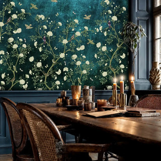 Chinoiserie garden wall mural with white florals and golden birds on teal, in elegant dining room with wicker chairs