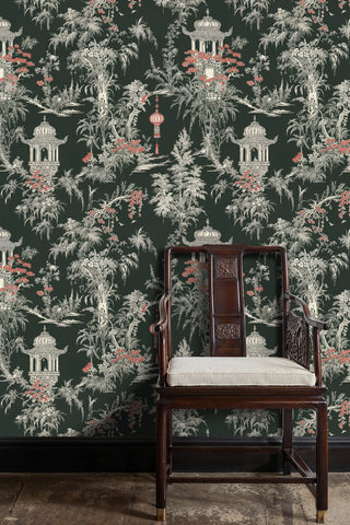 Chinoiserie garden wallpaper with ivory palms and red blooms on dark ground, beside a carved wooden chair