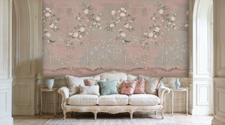 Chinoiserie garden wallpaper with songbirds and peonies on soft pink background, displayed in elegant French living room with ornate sofa