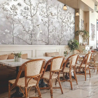 Chinoiserie wall mural, birds amid branches in grey and beige, in a cafe with marble tables