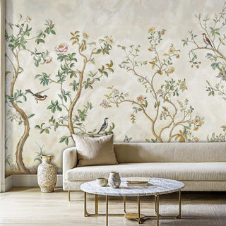 Chinoiserie wall mural with birds and trees in a living room with a beige sofa and a marble coffee table.