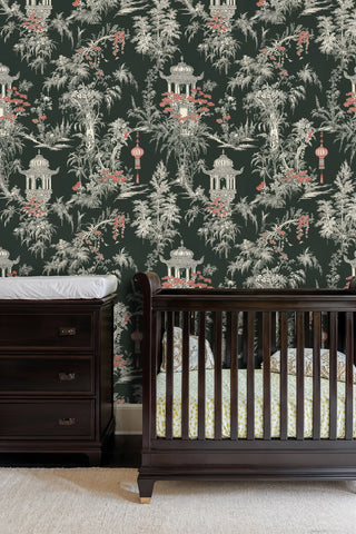Chinoiserie wallpaper featuring ornate pagodas and hanging lanterns on dark background, in a nursery with crib
