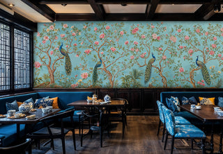 Chinoiserie wallpaper with peacocks and pink flowers on turquoise, shown in elegant restaurant with blue banquettes