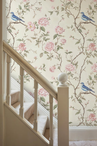 Classic floral wallpaper with pink roses and blue birds, shown along stairway with wooden banister