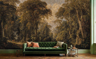 Classical forest landscape wall mural with golden trees and dramatic sky, displayed behind green velvet sofa