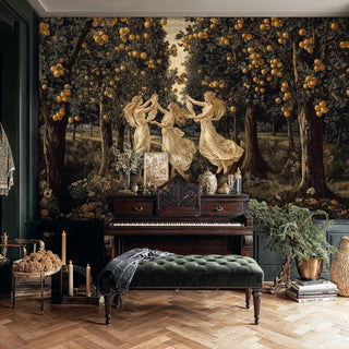 Classical muses wallpaper featuring three dancing figures in flowing robes beneath golden fruit trees, displayed in an elegant room with green tufted bench and antique piano