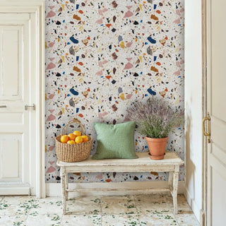 Colorful terrazzo wallpaper with pink and navy accents, displayed in bright entryway with white distressed bench