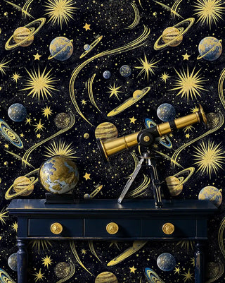 Cosmic universe wallpaper with golden planets and starbursts on black background, displayed in office with telescope