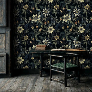Dark botanical clematis wallpaper with cream flowers on navy background, shown in vintage study with antique desk