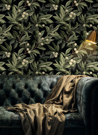 Dark botanical wallpaper featuring berry branches and foliage, displayed in luxurious living room with velvet sofa