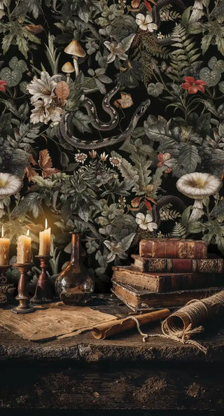 Dark botanical wallpaper featuring serpents, white florals, and mushrooms on black background in vintage study with candles and books