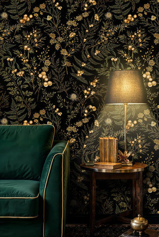 Dark botanical wallpaper with gold berries and green ferns, shown in a living room with green armchair and lamp