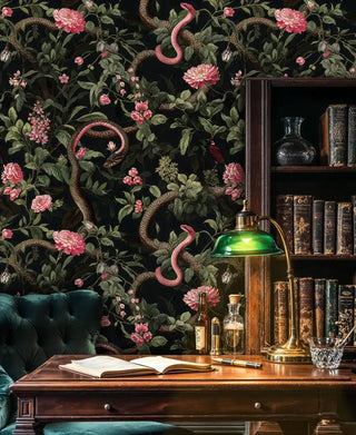 Dark botanical wallpaper with pink flowers and serpents, displayed in classic study with antique bookshelf