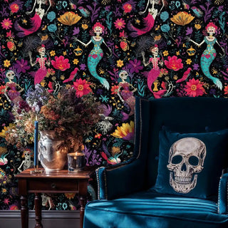 Dark floral mermaid skeleton wallpaper with teal and fuchsia mermaids, shown in sophisticated living room with blue velvet chair