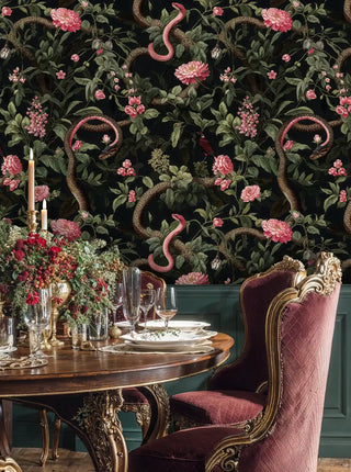 Dark floral serpent wallpaper in pink and black, shown in elegant dining space with burgundy upholstered chair