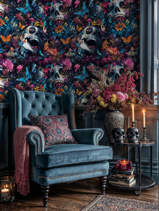 Dark floral skull wallpaper featuring colorful blooms in elegant study with blue armchair and skull decor