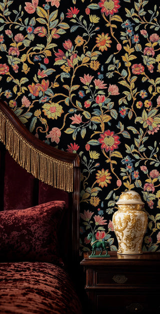 Dark floral tapestry wallpaper with colorful blooms and vines on black, in a luxury bedroom with velvet chaise and porcelain vase