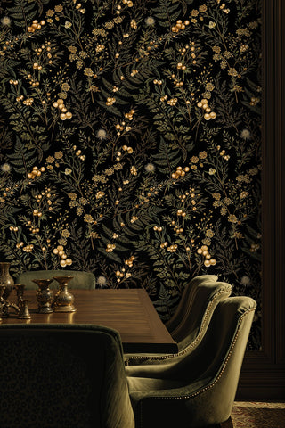 Dark floral wallpaper with golden berries and greenery, displayed in a dining room with velvet chairs and vases